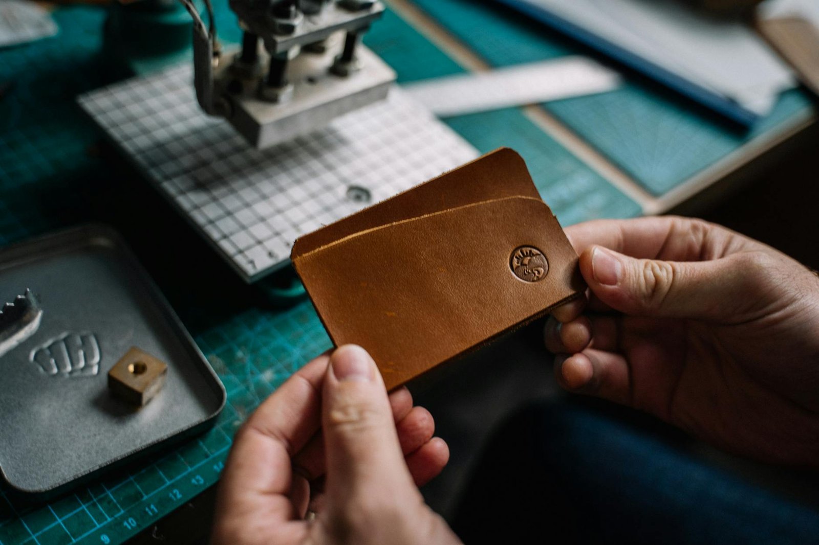 person holding brown leather wallet with embossed brand logo